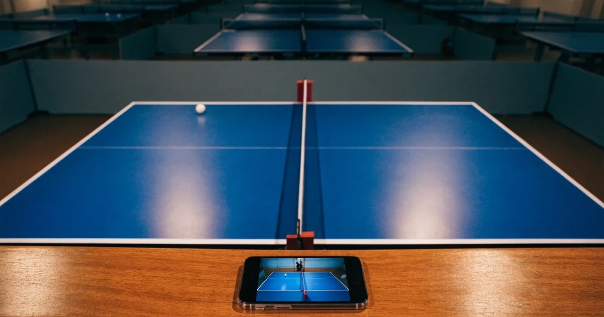 Eine Tischtennishalle aus erhöhter Perspektive mit mehreren blauen Tischen in Reihen unter gedämpftem Hallenlicht, ohne Personen.