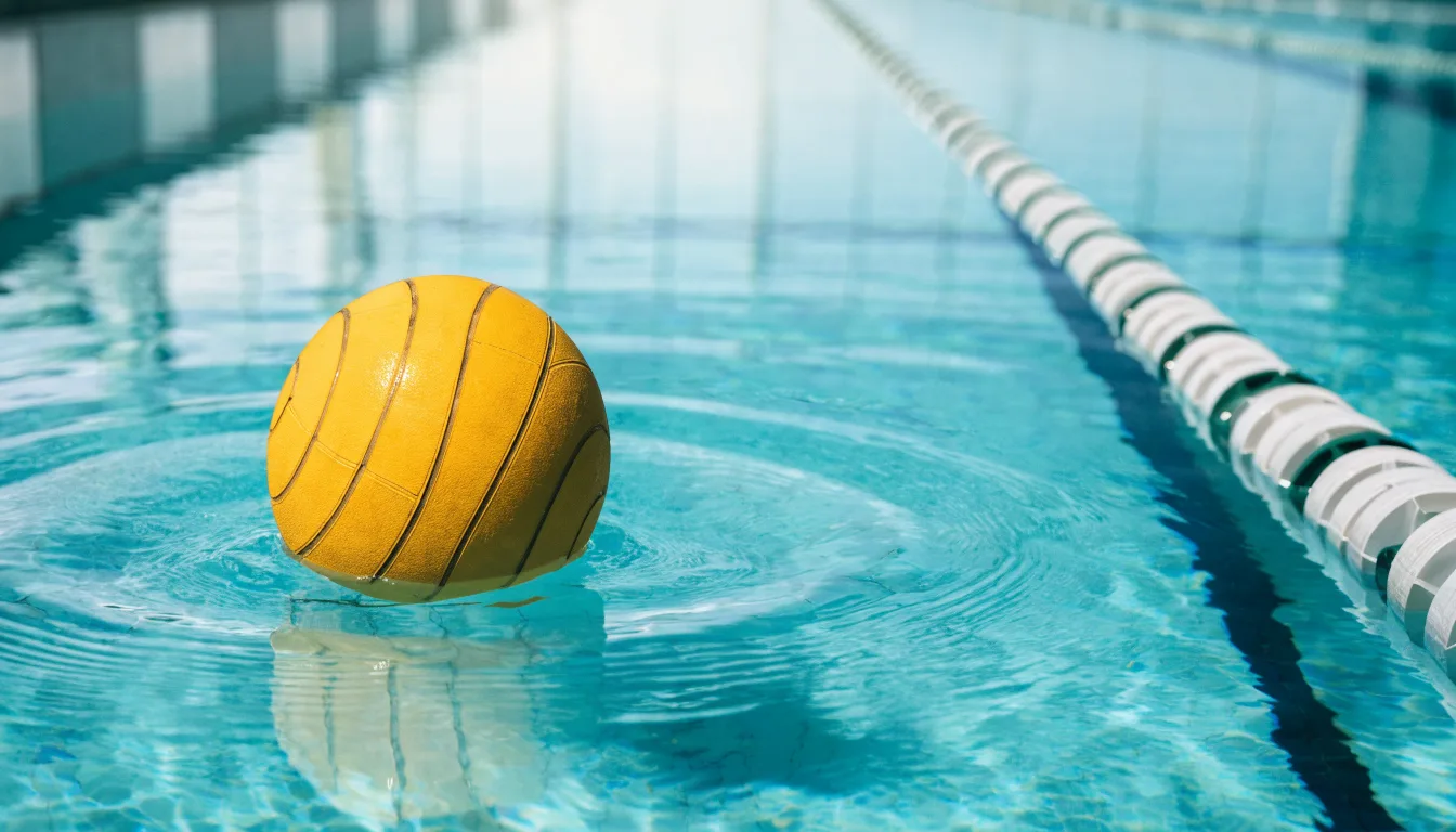 Ein gelber Wasserball treibt in Nahaufnahme auf der Wasseroberfläche neben einer Leine mit Bojen.
