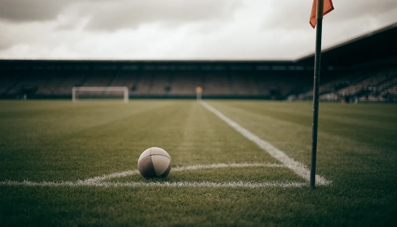 Ein Fußball liegt neben einer Eckfahne auf kurz gemähtem Rasen unter bewölktem Himmel.